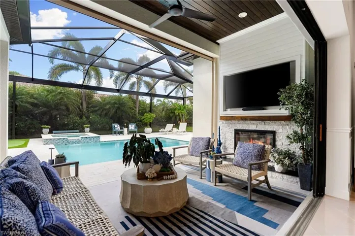 View of swimming pool featuring a patio, a lanai, a sunroom, a pool with connected hot tub, and an outdoor living space with a fireplace
