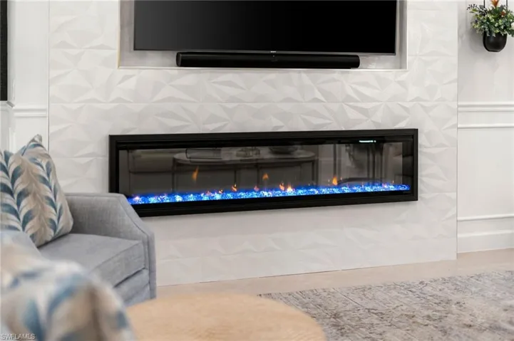 Detailed view of a glass covered fireplace, a wainscoted wall, and a decorative wall