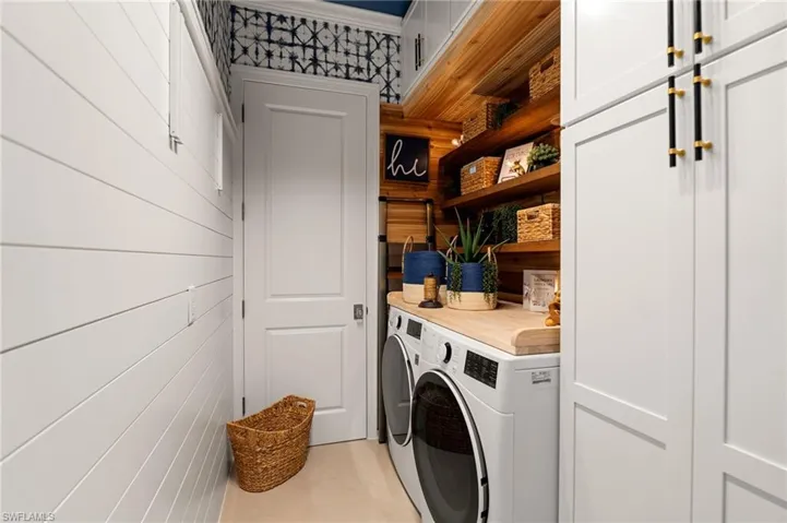 Laundry area featuring washer and dryer, ornamental molding, and wood walls