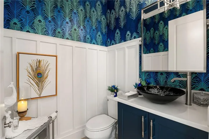 Half Bathroom with a decorative wall, wallpapered walls, a wainscoted wall, and vanity