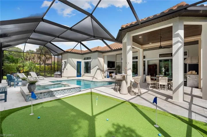 Back of house with a putting area, a ceiling fan, a tile roof, a pool with connected hot tub, and outdoor dining space