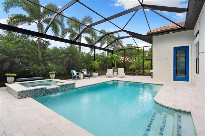 View of swimming pool with a patio area, a pool with connected hot tub, a sunroom, and glass enclosure