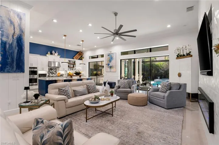Living area featuring a decorative wall, ornamental molding, a ceiling fan, recessed lighting, and a wainscoted wall