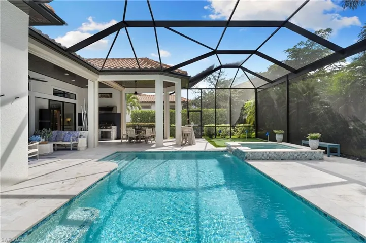 View of swimming pool with a patio, a sunroom, a lanai, exterior kitchen, and a pool with connected hot tub