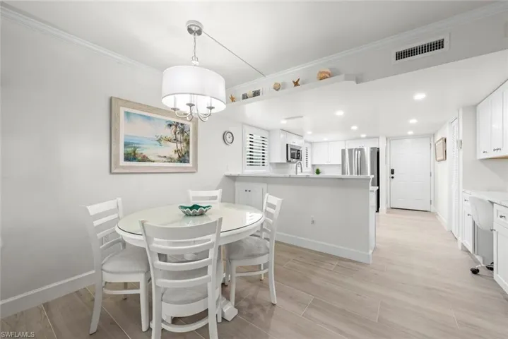 Open-concept dining and kitchen area with light wood-finish flooring, recessed lighting, and a white kitchen island