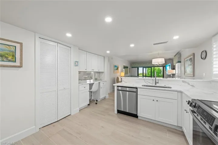 Modern kitchen featuring white cabinetry, light-toned wood-finish flooring, and a stainless steel dishwasher