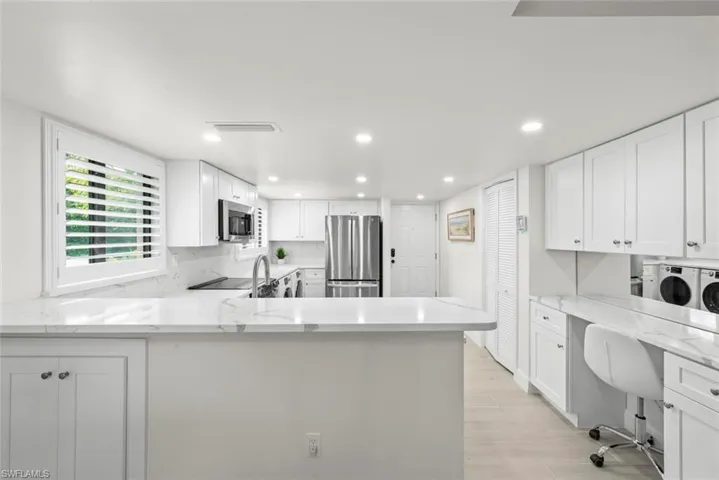 Modern kitchen featuring white shaker cabinetry, stainless steel appliances, marble-look countertops, and recessed lighting