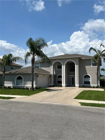View of front of home with concrete driveway, stucco siding, and a front lawn