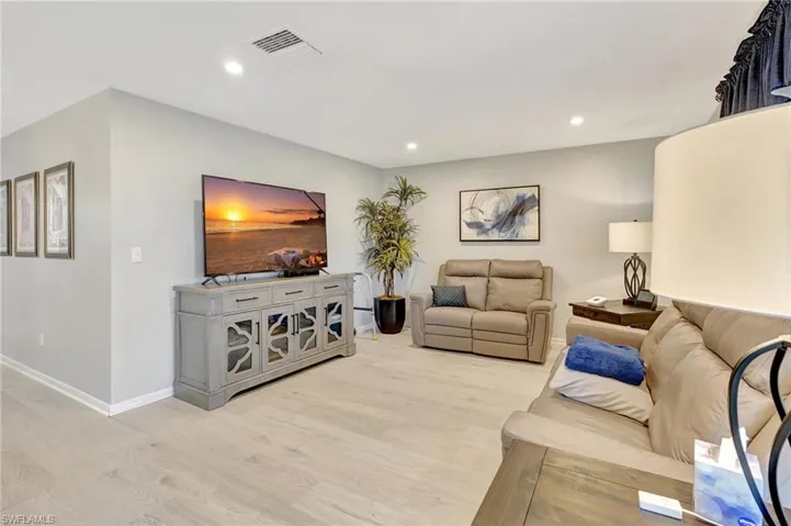 Living area with light wood finished floors and recessed lighting