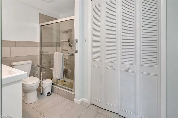Full bath with a closet, a stall shower, tile patterned flooring, and tile walls