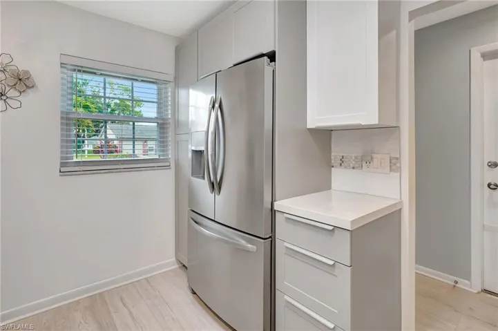 Kitchen featuring stainless steel fridge with ice dispenser, light countertops, light wood-style flooring, and white cabinetry