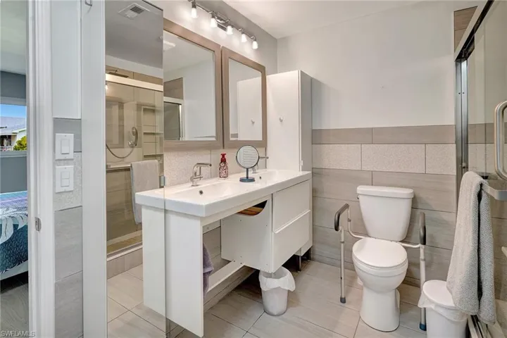 Bathroom with tile walls, a shower stall, tile patterned flooring, and vanity