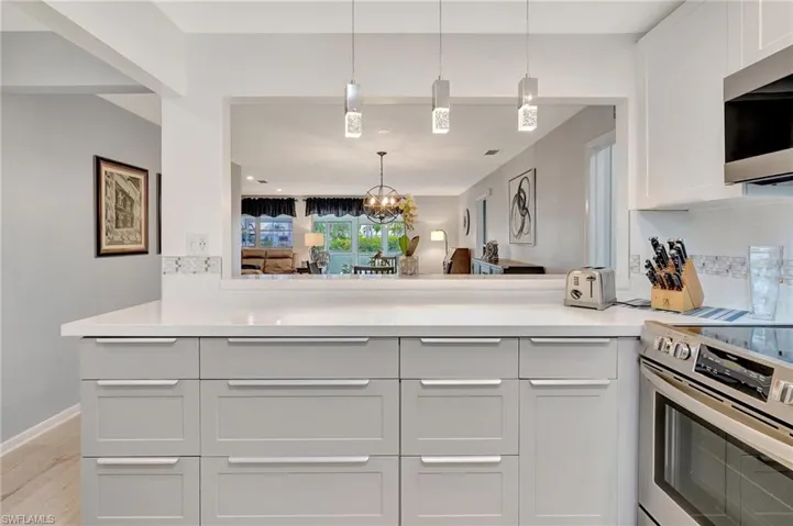 Kitchen featuring appliances with stainless steel finishes, a chandelier, light countertops, and backsplash