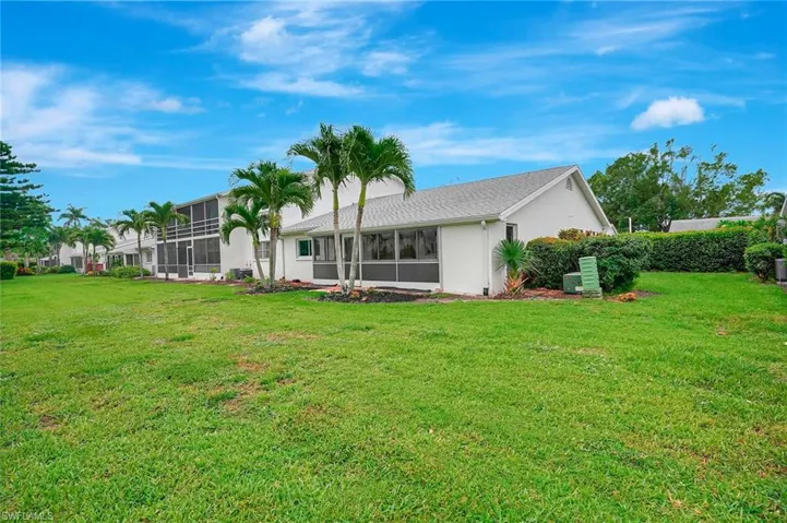 Rear view of house with a yard, stucco siding, and a sunroom