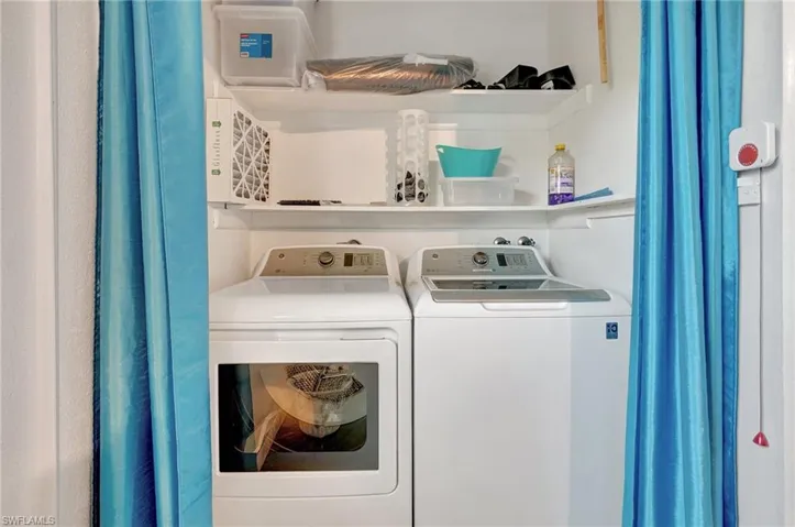 Laundry room featuring washing machine and clothes dryer that is located in the garage