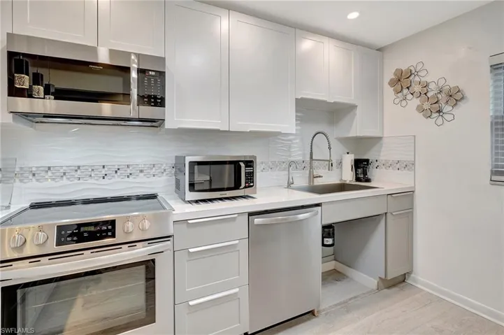 Kitchen with appliances with stainless steel finishes, light countertops, decorative backsplash, light wood finished floors, and recessed lighting