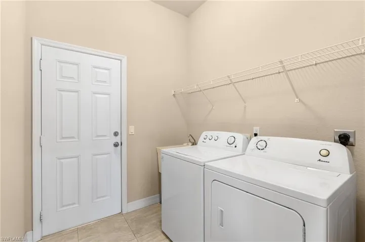 Clothes washing area with light tile patterned floors and washing machine and clothes dryer