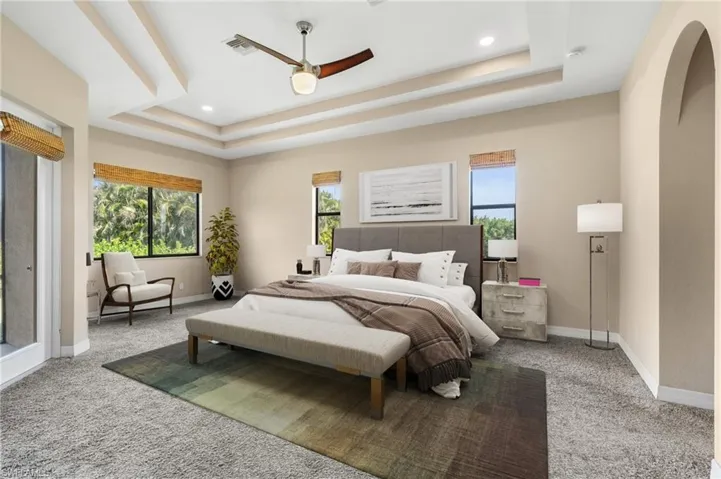 Carpeted bedroom with ceiling fan and a raised ceiling