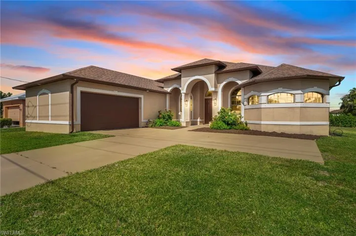 View of front of property featuring a garage and a lawn