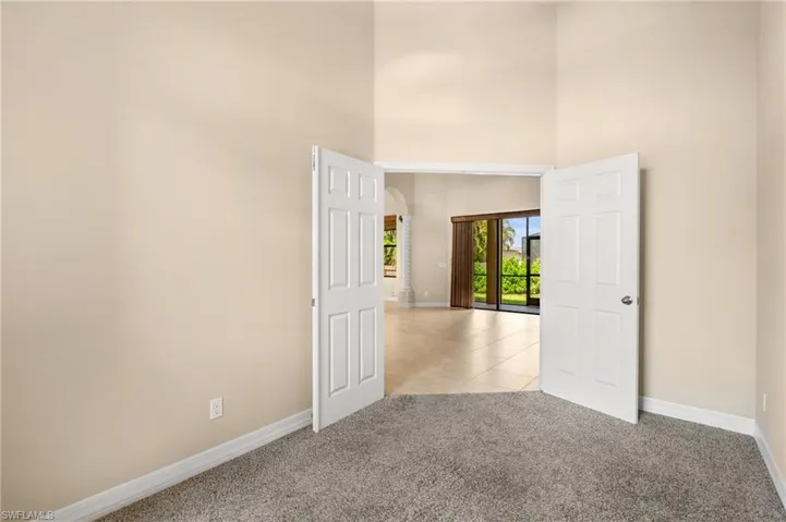 Empty room with light carpet and a towering ceiling