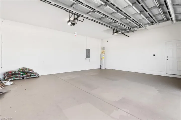 Garage featuring a garage door opener, electric panel, and water heater