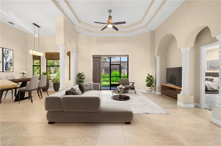 Living room with ceiling fan, plenty of natural light, decorative columns, and a towering ceiling