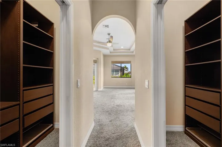 Hallway with a tray ceiling and light colored carpet