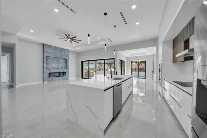 Kitchen featuring modern cabinets, hanging light fixtures, light marble finish floors, a raised ceiling, and recessed lighting