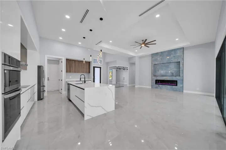 Kitchen with modern cabinets, decorative light fixtures, recessed lighting, light stone counters, and a ceiling fan
