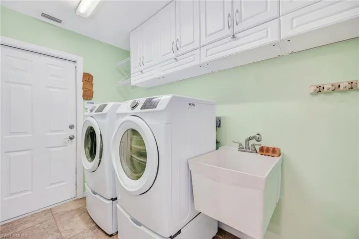 Washroom featuring independent washer and dryer and cabinet space
