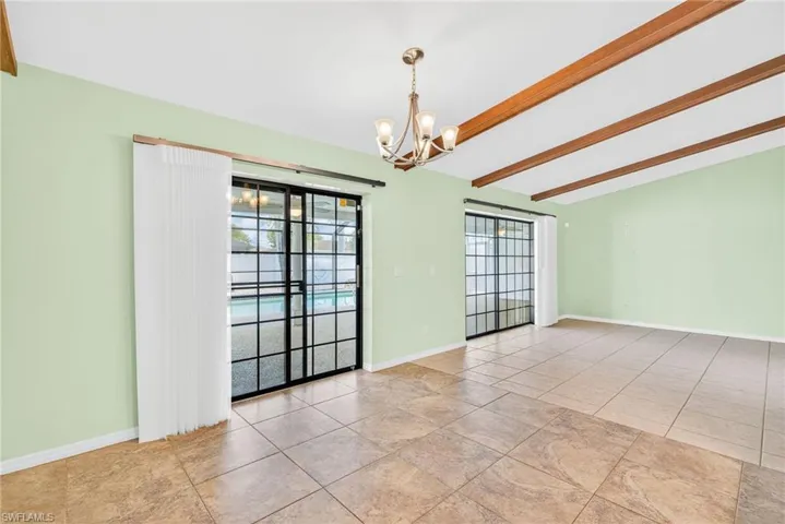 Empty room featuring beam ceiling and a chandelier