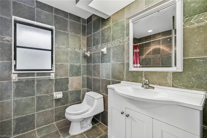 Bathroom featuring curtained shower, vanity, tile walls, and tile patterned floors
