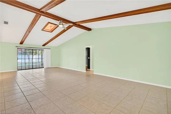 Spare room featuring beamed ceiling, light tile patterned flooring, high vaulted ceiling, and a ceiling fan