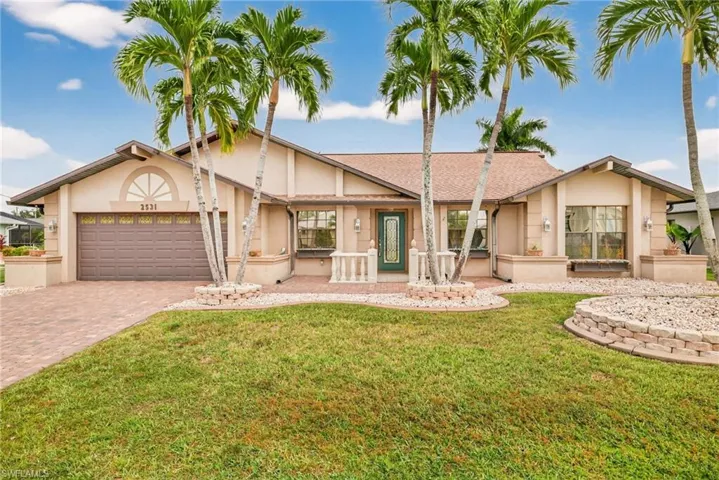 Ranch-style house featuring a front lawn, stucco siding, decorative driveway, and an attached garage