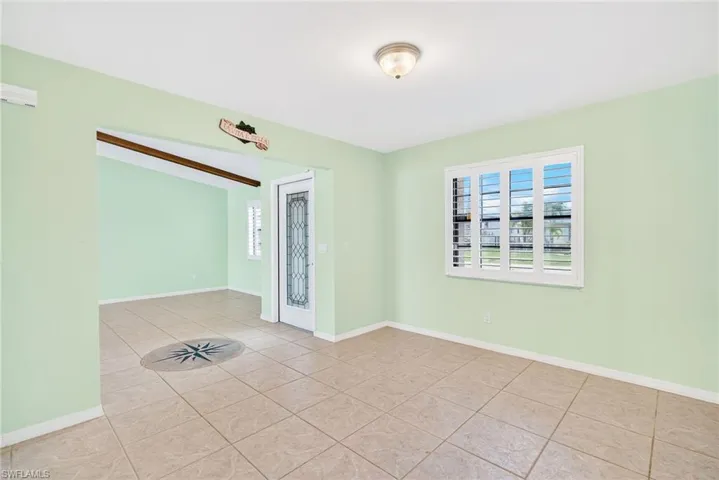 Empty room featuring light tile patterned flooring and beam ceiling