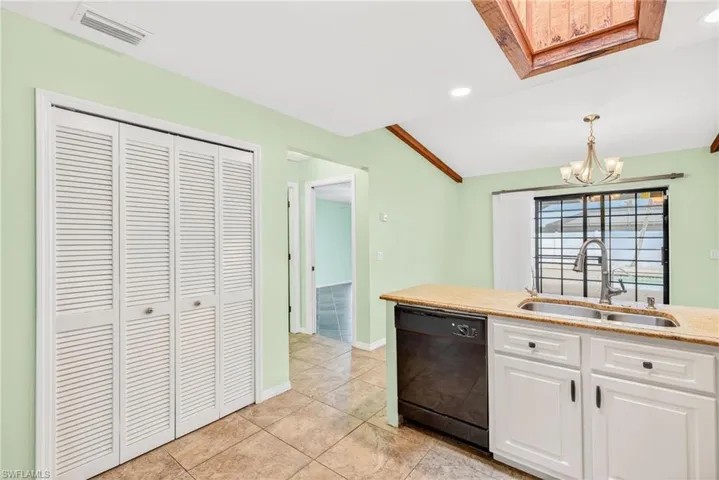 Kitchen featuring white cabinets, black dishwasher, a chandelier, recessed lighting, and light stone counters