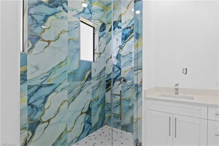 Bathroom featuring a marble finish shower and vanity
