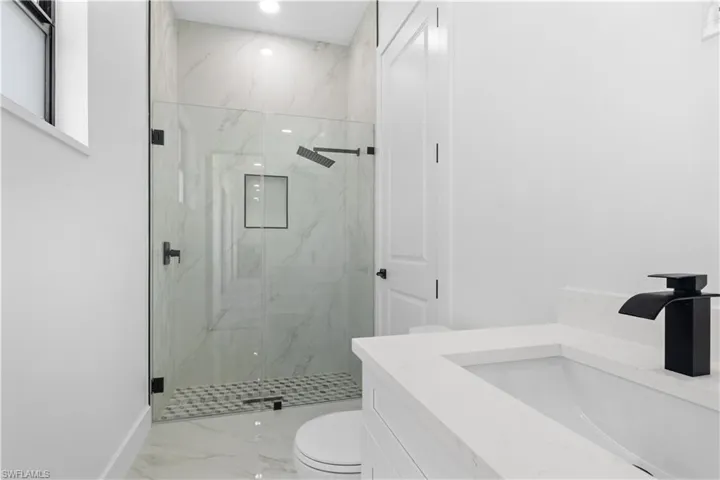 Full bathroom with baseboards, marble finish floor, a marble finish shower, and toilet