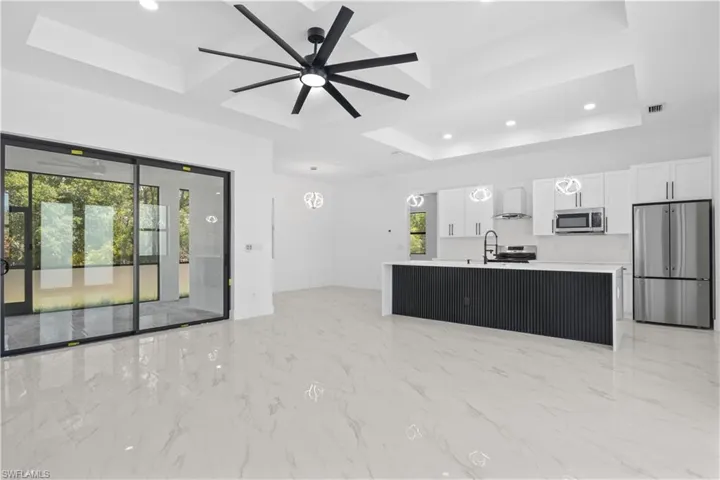 Living area featuring a raised ceiling, a ceiling fan, recessed lighting, visible vents, and coffered ceiling