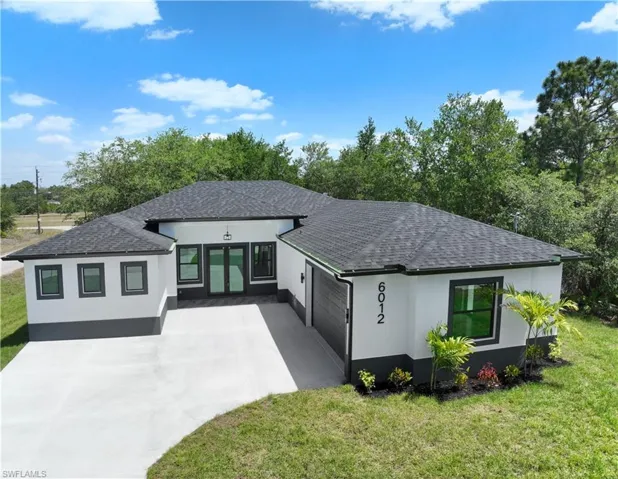 Prairie-style house with stucco siding, roof with shingles, and a garage