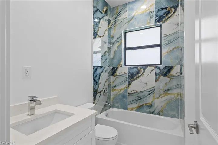 Bathroom featuring washtub / shower combination, vanity, and toilet
