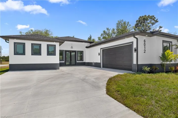 View of front facade with a garage, stucco siding, driveway, and a front yard