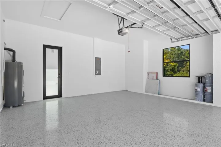 Garage featuring a garage door opener, water heater, and electric panel
