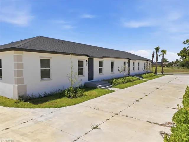 Contemporary exterior with white stucco finish, dark asphalt shingle roof, multiple windows, and a paved drive