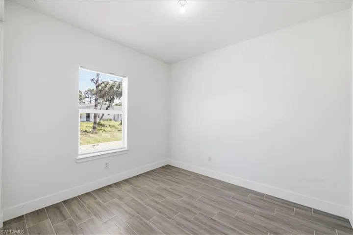 Room featuring wood-look tile flooring, white baseboards, a single window with blinds, and recessed lighting