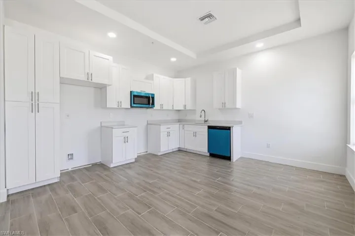 Kitchen featuring white cabinetry, light countertops, integrated sink, wood-finish tile flooring, and recessed lighting