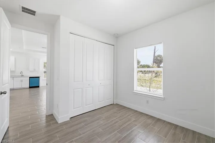 Light-filled room featuring wood-finish flooring, white walls, and a window with blinds