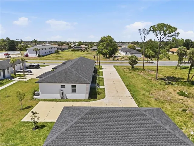 Aerial perspective showcasing multiple properties with dark shingle roofs and light-colored exteriors