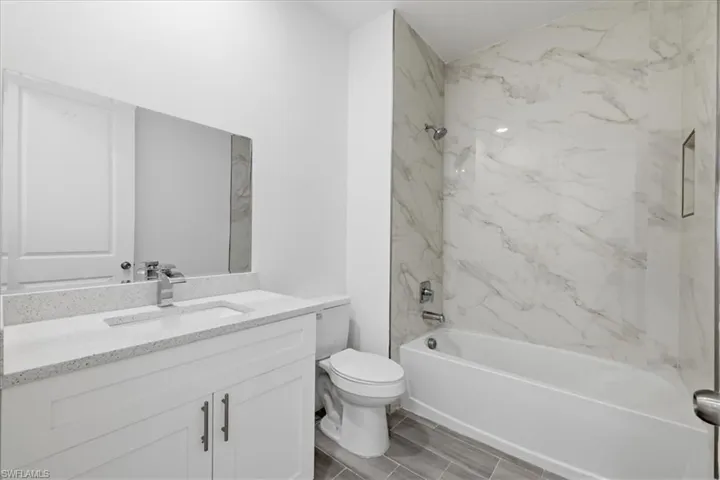 Bathroom featuring a white vanity with shaker-style cabinetry, a speckled countertop, and an integrated sink with a chrome faucet