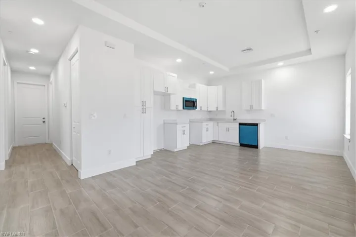Open-concept living space featuring wood-finish tile flooring and a tray ceiling